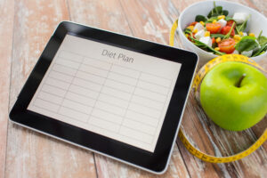 Close Up Of Diet Plan On Tablet Pc And Food